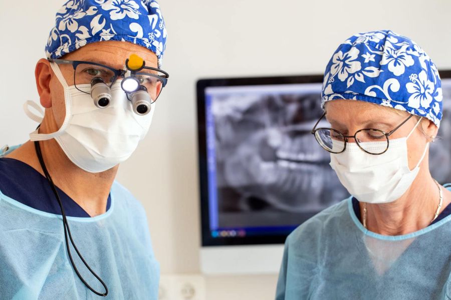 Hochkonzentrierte Teamarbeit bei einer Zahnoperation Operation in der Zahnarztpraxis Heitmüller. Zahnarzt Philipp Heitmüller trägt eine Lupenbrille und wird durch eine Assistentin unterstützt.