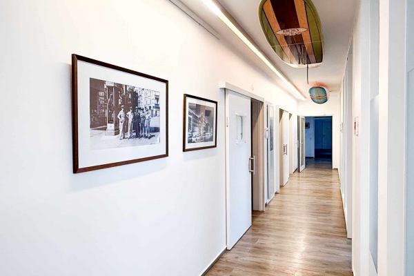 Heller Praxisflur der Zahnarztpraxis Heitmüller, Hannover List, mit historischen Fotografien an der Wand und dekorativen Surfbrettern an der Decke.